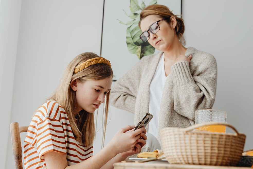 Adolescente usando o celular enquanto é observada pela mãe — Foto: Karolina Grabowska / Pexels