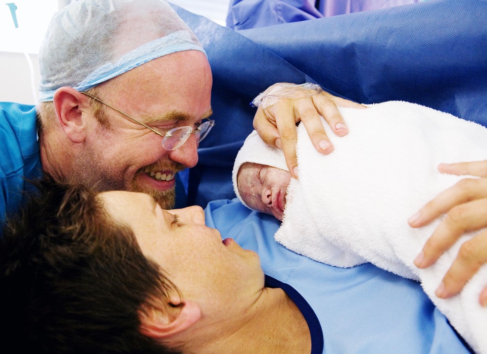 Mãe e pai veem recém-nascido pela primeira vez depois de uma cesárea  — Foto: Getty Images