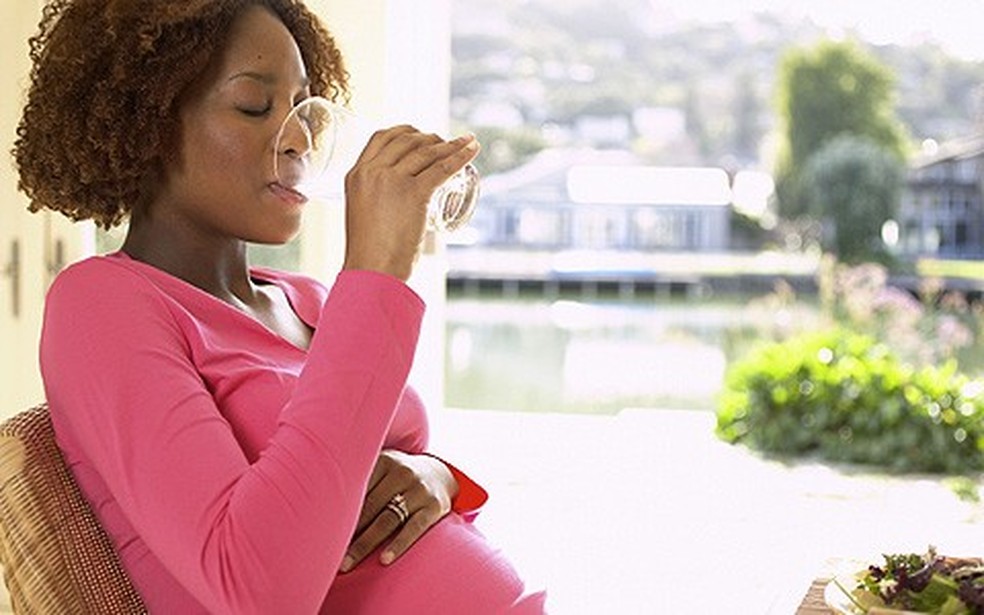 Mulher grávida sentada bebendo água (Foto: Shutterstock) — Foto: Crescer