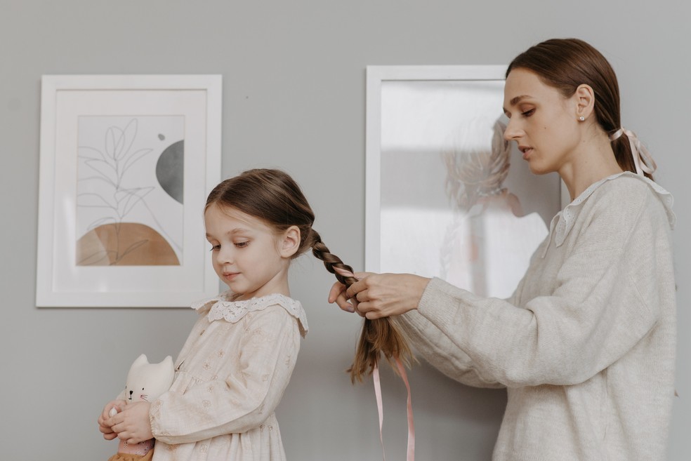 Mãe arrumando o cabelo da filha — Foto: Pexels