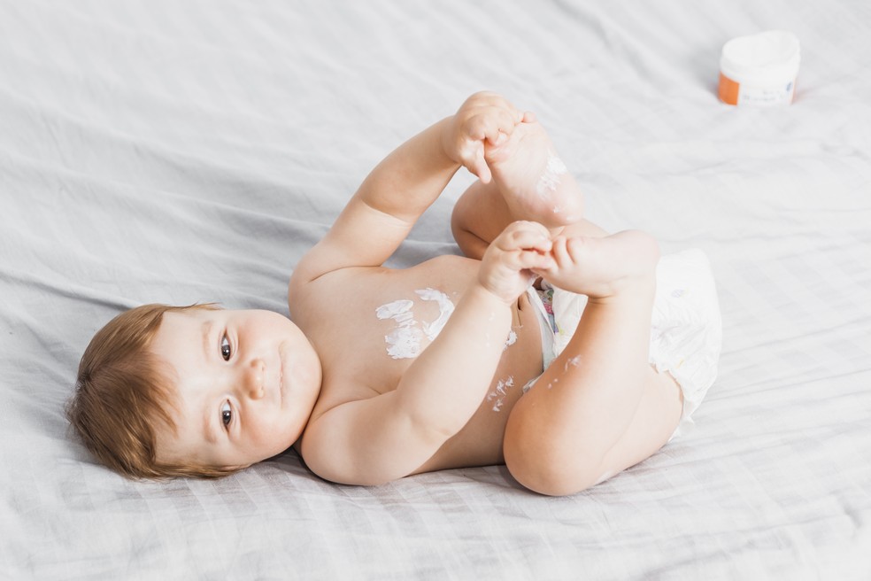 Bebê segurando a ponta dos dedos dos pés — Foto: Freepik