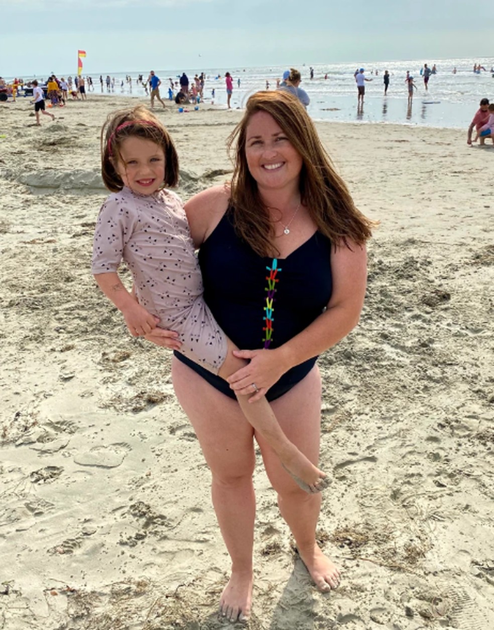 Emiliana Hall com a filha, na praia — Foto: Reprodução/Metro