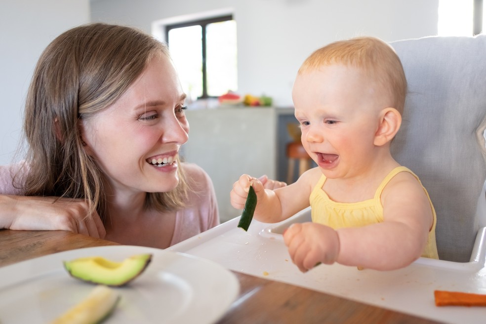 Bebê comendo abacate ao lado da mãe — Foto: Freepik
