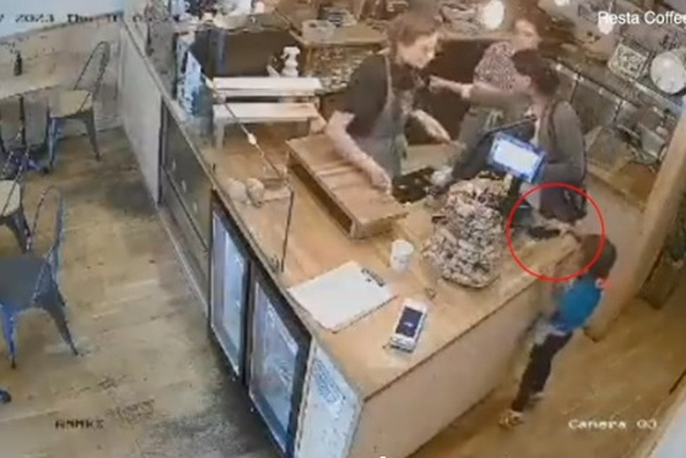 Criança pega celular enquanto mulher distrai funcionárias de loja — Foto: Reprodução/Daily Mail