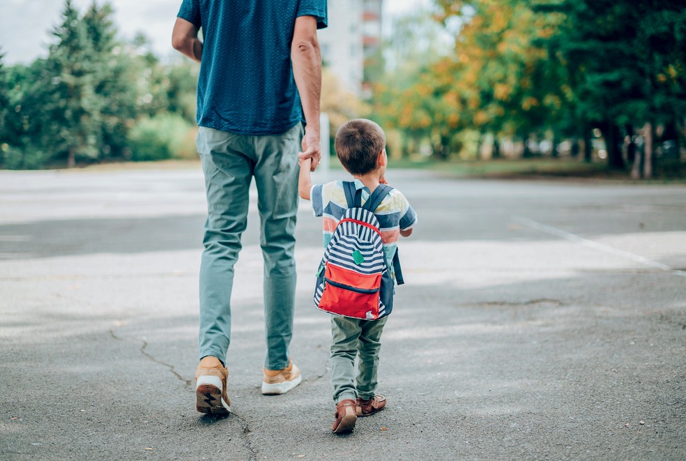 Pai levando o filho para a escola — Foto: Getty Images